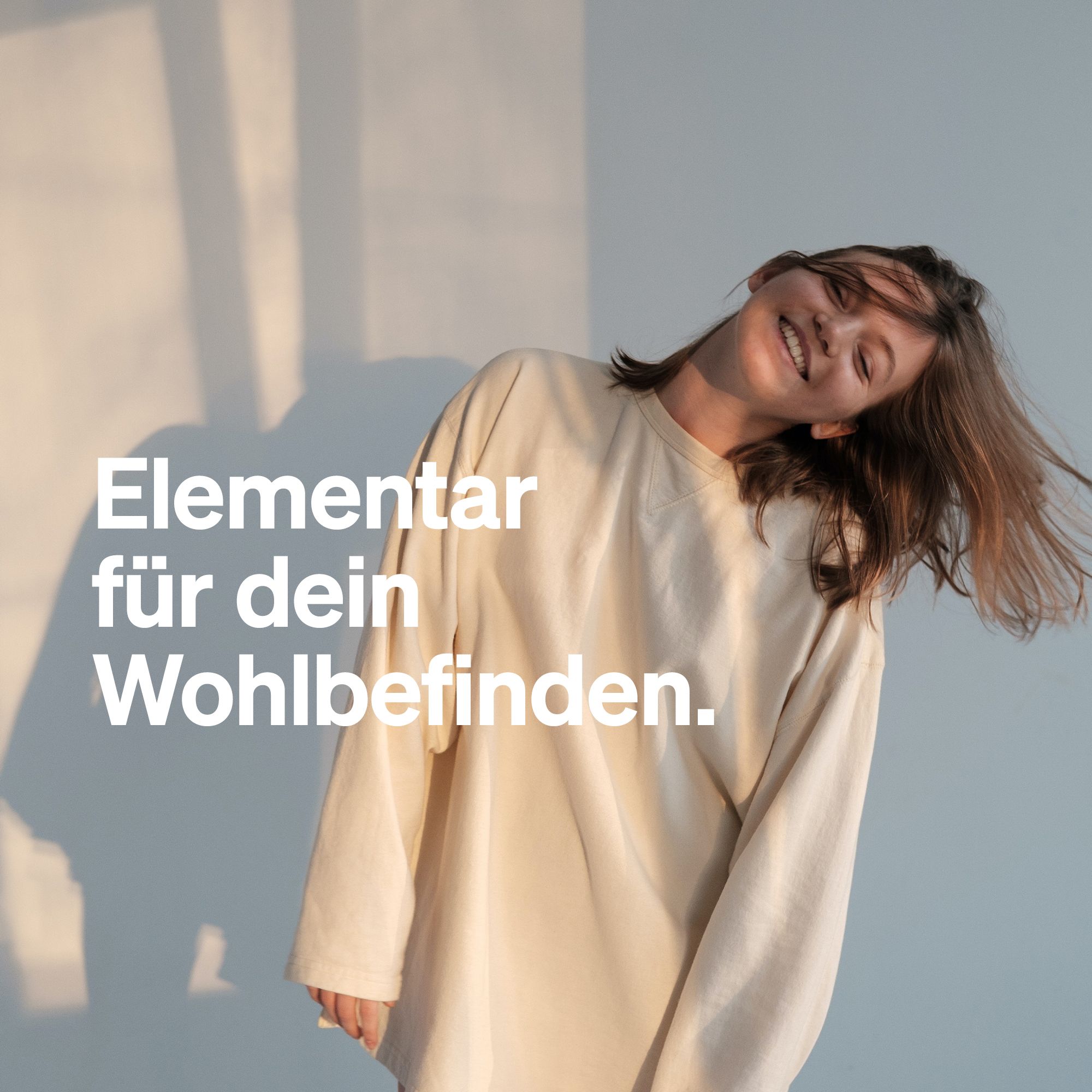 Eine lächelnde Frau mit wehenden Haaren. Text: Elementar für dein Wohlbefinden.