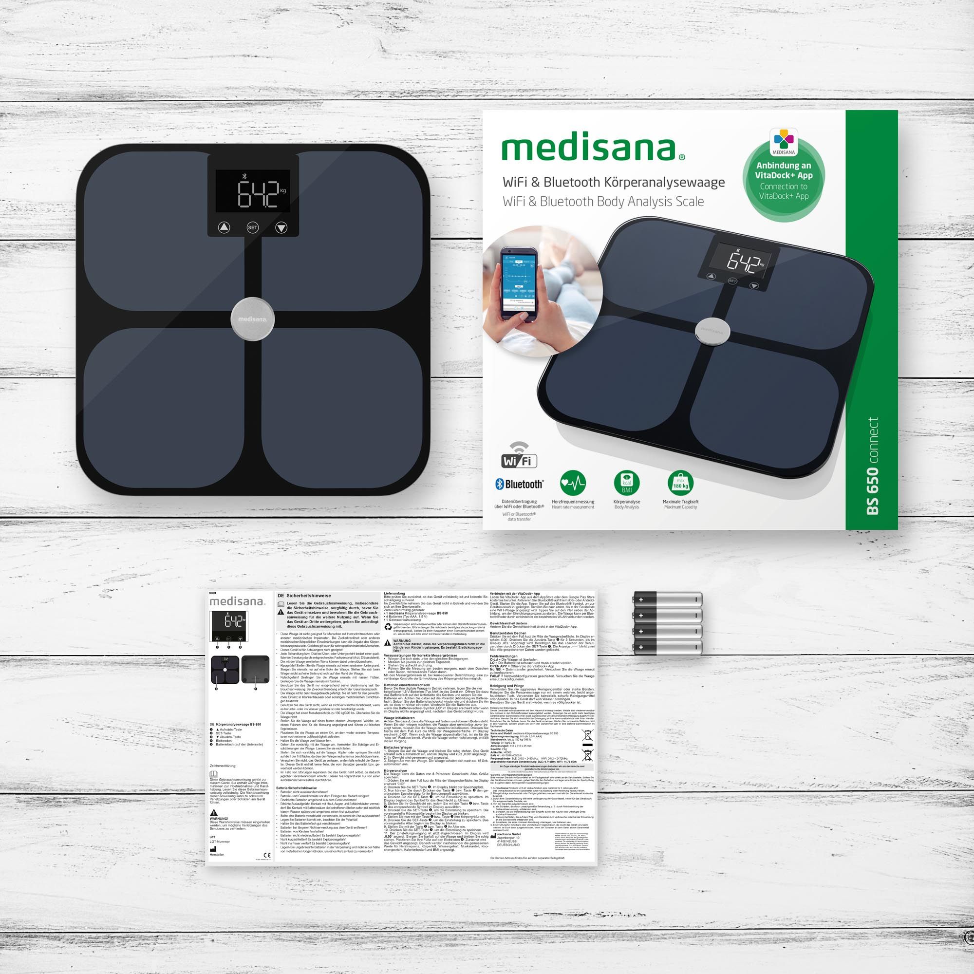 Körperanalysewaage mit Verpackung und Anleitung. Waage ist schwarz mit Glasoberfläche und LCD-Display.