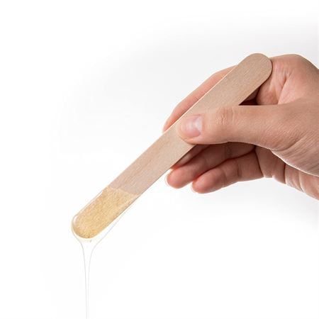 Hand hält einen Holzspatel mit Wachs.