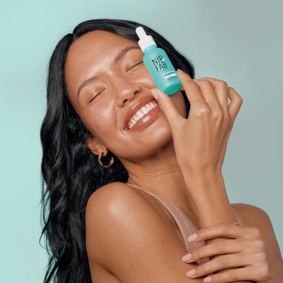 Frau hält eine grüne Flasche mit weißem Deckel. Sie lächelt. Hintergrund: hellblau.