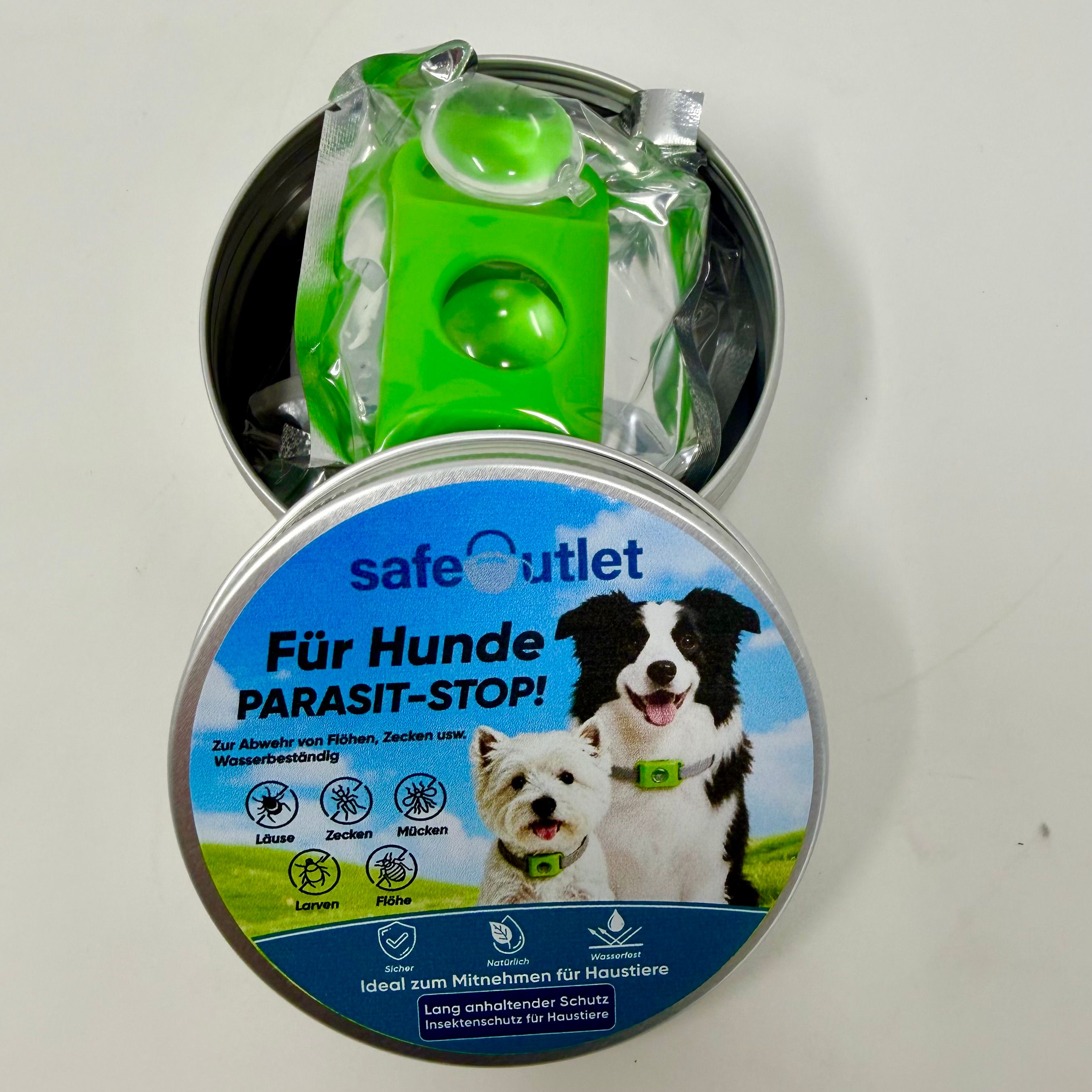 Offene Safeoutlet Dose mit Hundehalsband und grünem Applikator für Parasitenschutz.