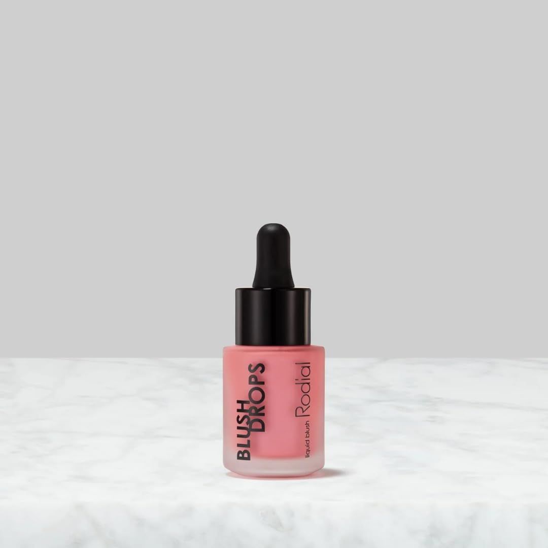 Rosa Flüssigrouge-Flasche mit schwarzem Applikator. Produktname und Marke sichtbar.
