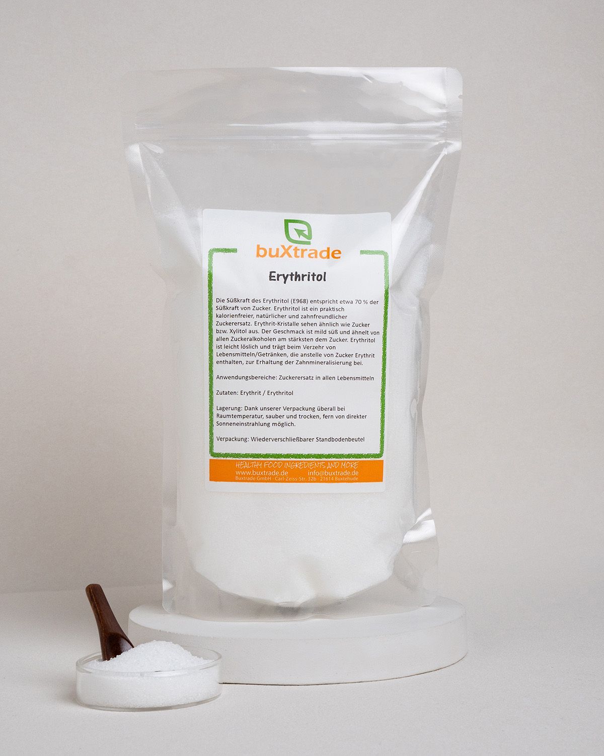 Transparente Verpackung mit buXtrade Erythritol. Weißes Pulver. Kleiner Löffel und Schale mit Erythritol.