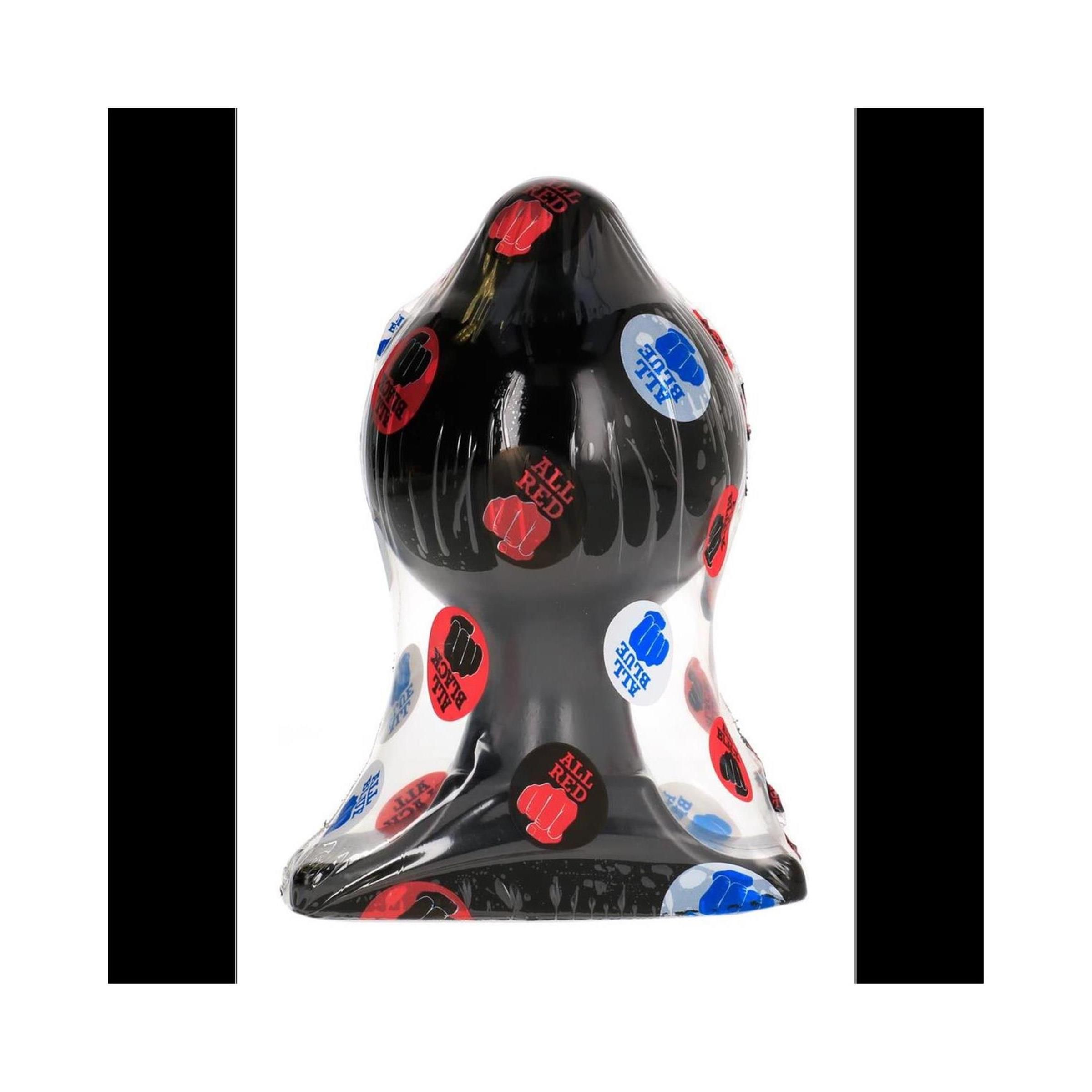 Schwarzer Analplug, verpackt in Folie. Rote, blaue und weiße Aufkleber mit Text und Faust-Symbol.