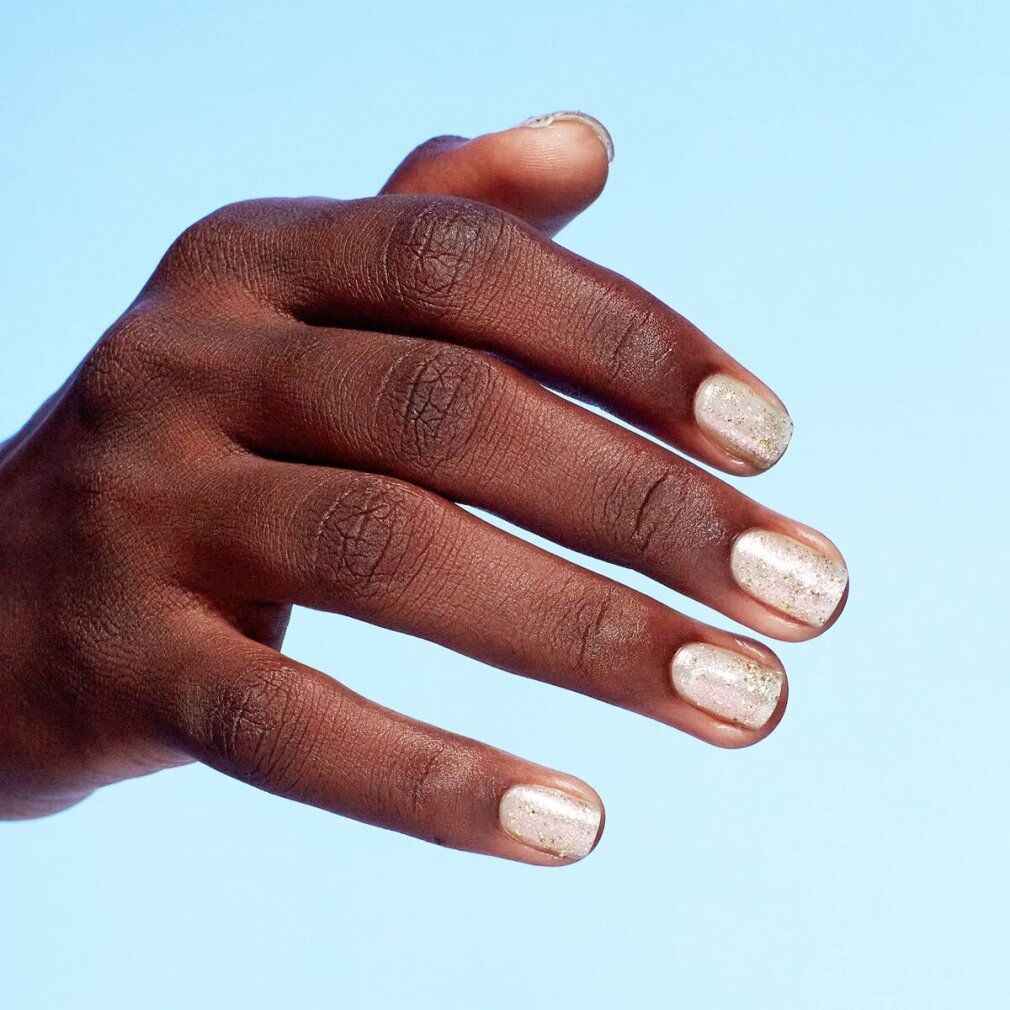 Hand mit lackierten Fingernägeln. Nagellack mit Glitzerpartikeln.