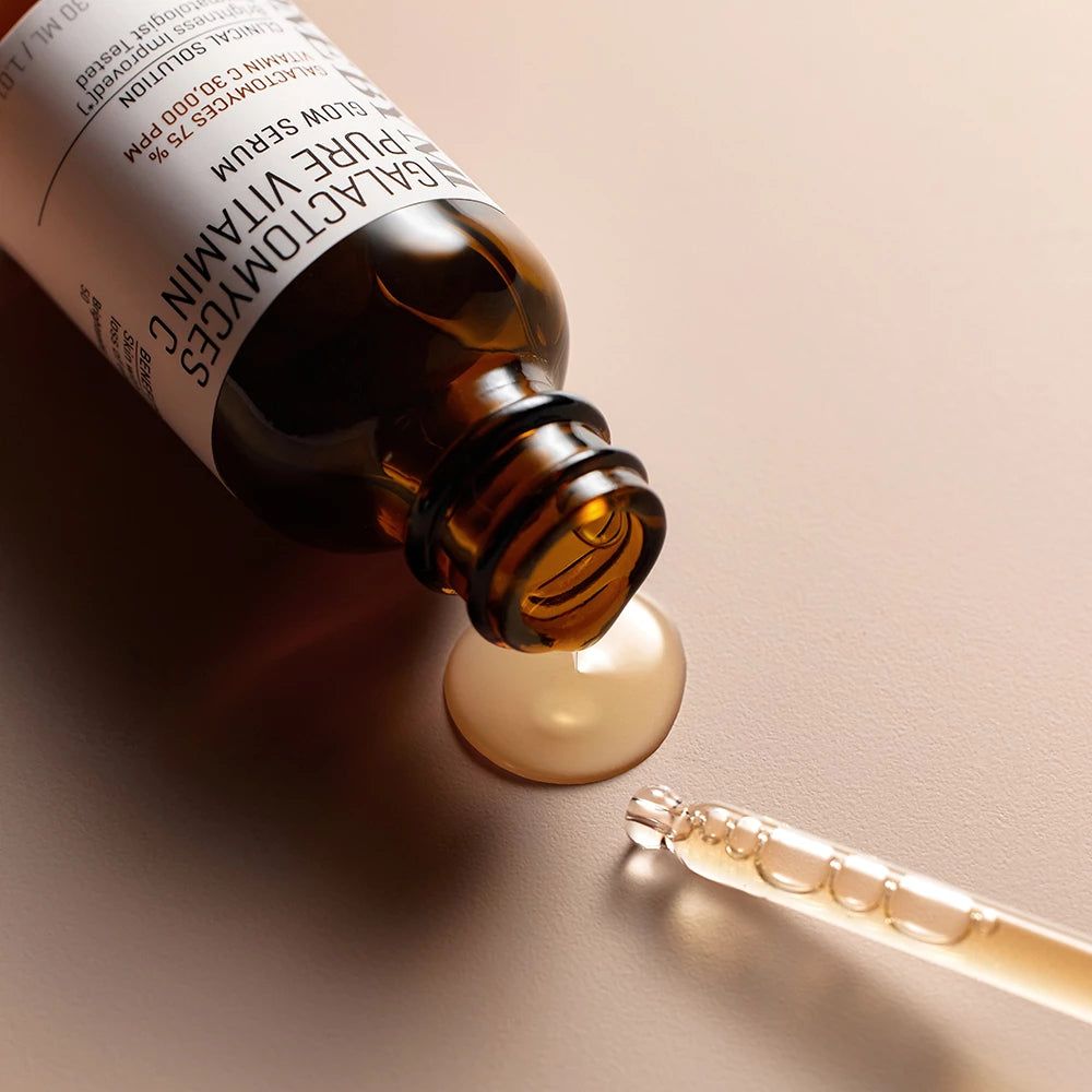 Braune Glasflasche mit schwarzem Tropfer. Serum tropft auf eine Oberfläche. Tropfer daneben.