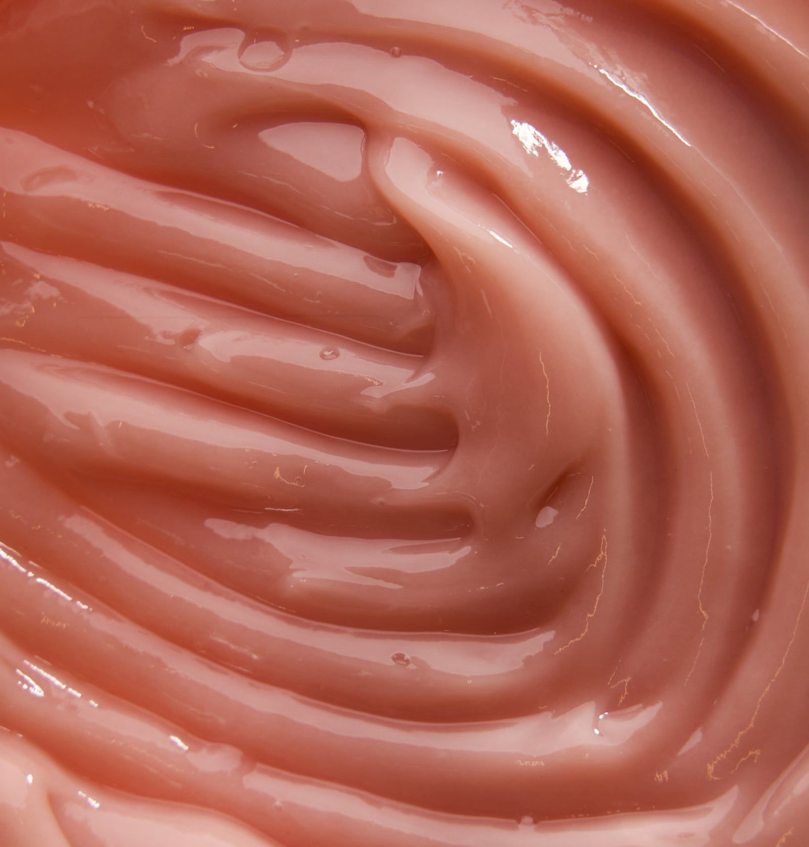 Nahaufnahme einer rosa, cremigen Substanz mit wellenförmiger Textur. Vermutlich Shampoo.