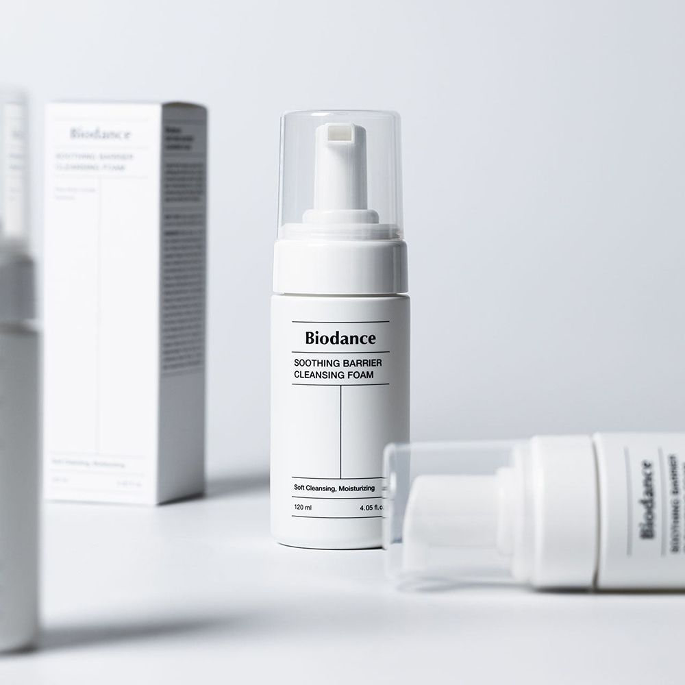Weiße Flasche und Verpackung. Aufschrift: BIODANCE, SOOTHING BARRIER CLEANSING FOAM. Flaschen liegen.