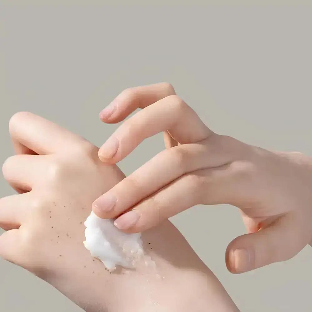 Hand trägt TIRTIR Hydro Boost Enzyme Reinigungsbalsam auf die andere Hand auf, die mit Sommersprossen bedeckt ist.