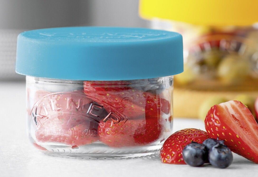 Glas mit blauem Deckel, gefüllt mit Erdbeeren. Daneben Erdbeeren und Blaubeeren. "KILNER" auf dem Glas.