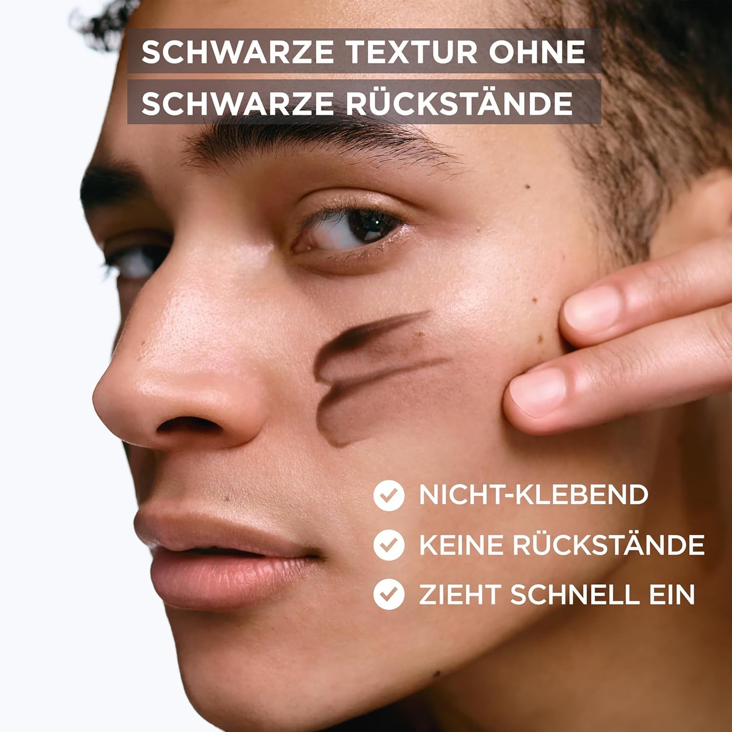 Mann trägt Creme auf. Schwarze Textur, nicht klebend, keine Rückstände, zieht schnell ein. Produktnamen nicht sichtbar.