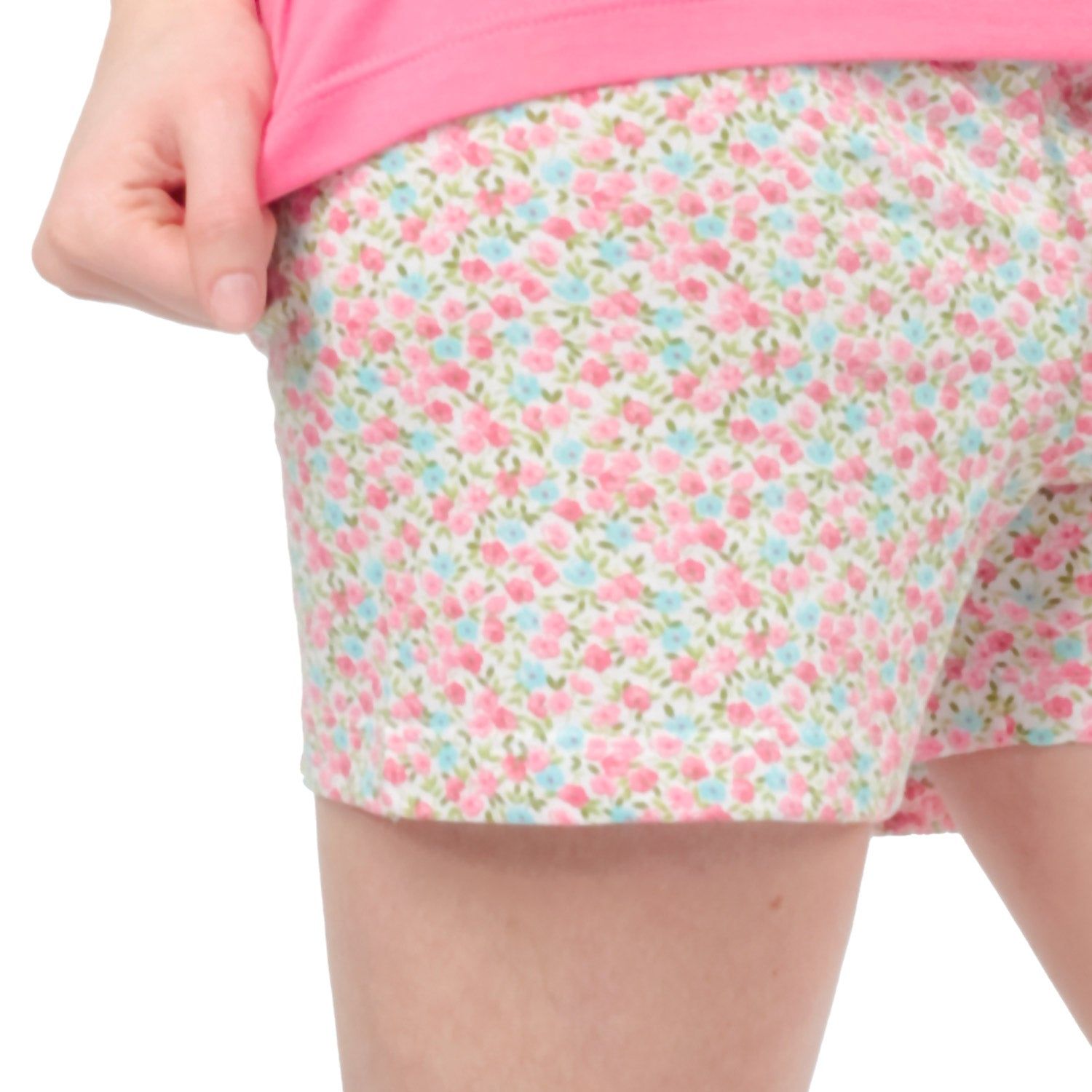 Nahaufnahme der floralen Shorts. Rosa und blaue Blumen auf weißem Grund. Frau hält Shorts fest.