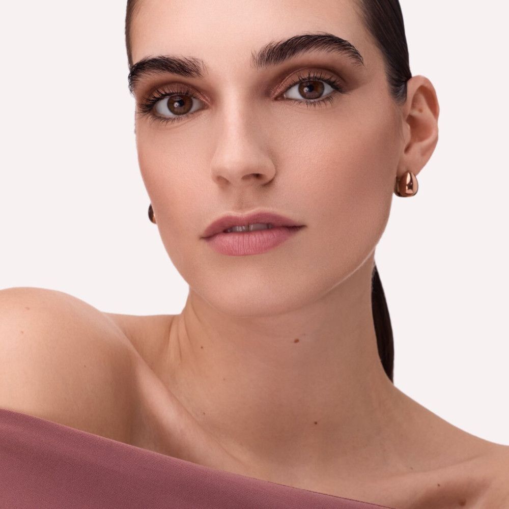 Nahaufnahme einer Frau mit Make-up. Fokus auf Augen und Lippen. Hautton, rosafarbene Lippen, dezentes Augen-Make-up.