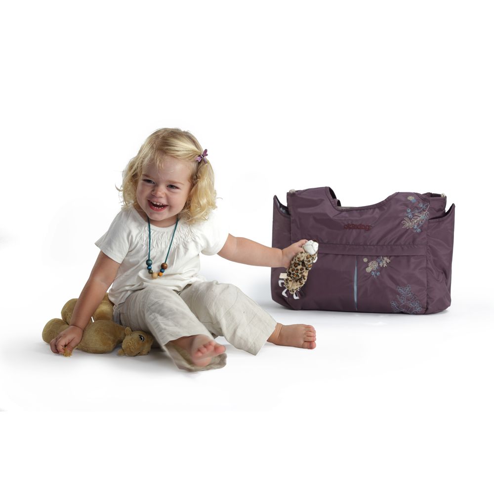Wickeltasche in Lila mit floralen Stickereien. Seitentaschen, Tragegriff und Schulterriemen. Kind sitzt daneben.