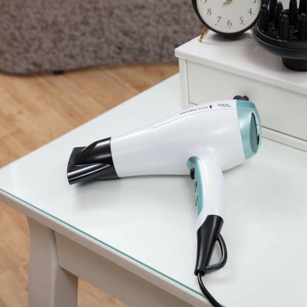 Weißer Haartrockner auf einem Tisch. Marke Remington. Blaue Akzente. Schwarzes Kabel.