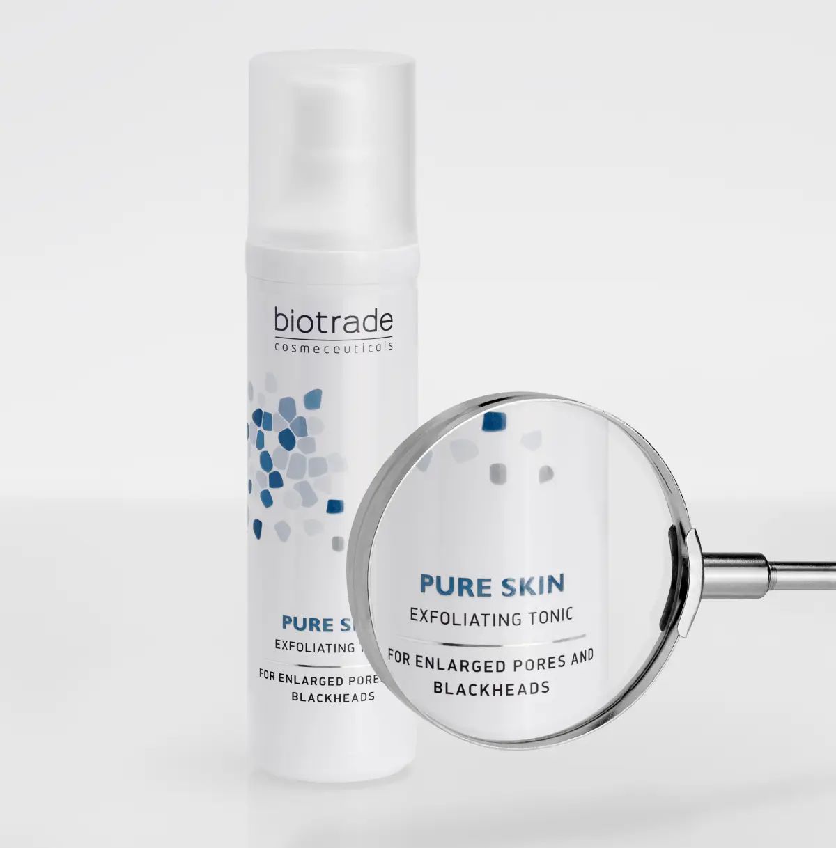 Weiße Flasche mit Sprühkopf und Lupe. Aufschrift: biotrade, Pure Skin Exfoliating Tonic, für vergrößerte Poren und Mitesser. Blaue Grafik.