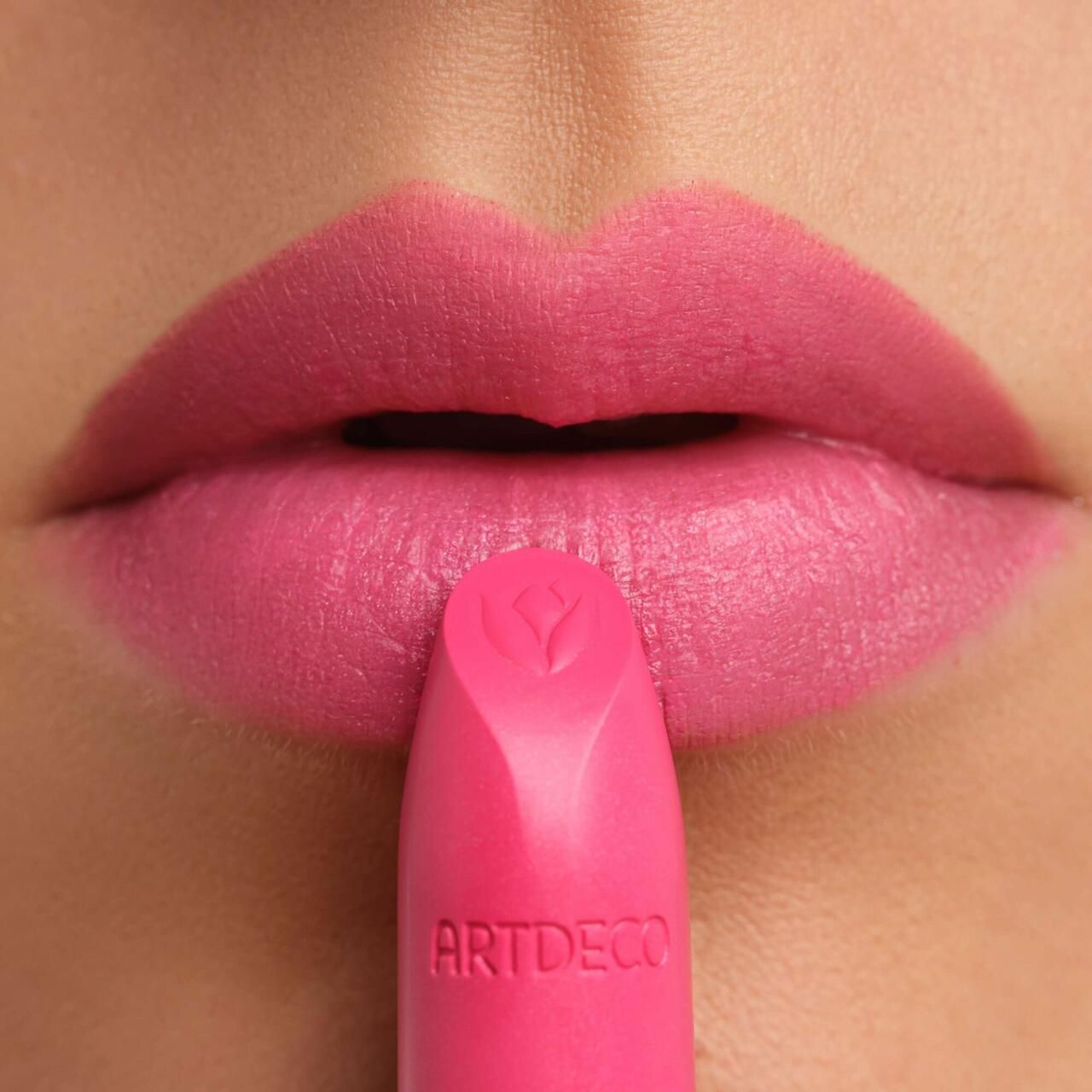 Lippenstift in Pink, mit Logo und Schriftzug ARTDECO. Lippen mit pinkem Lippenstift bemalt.