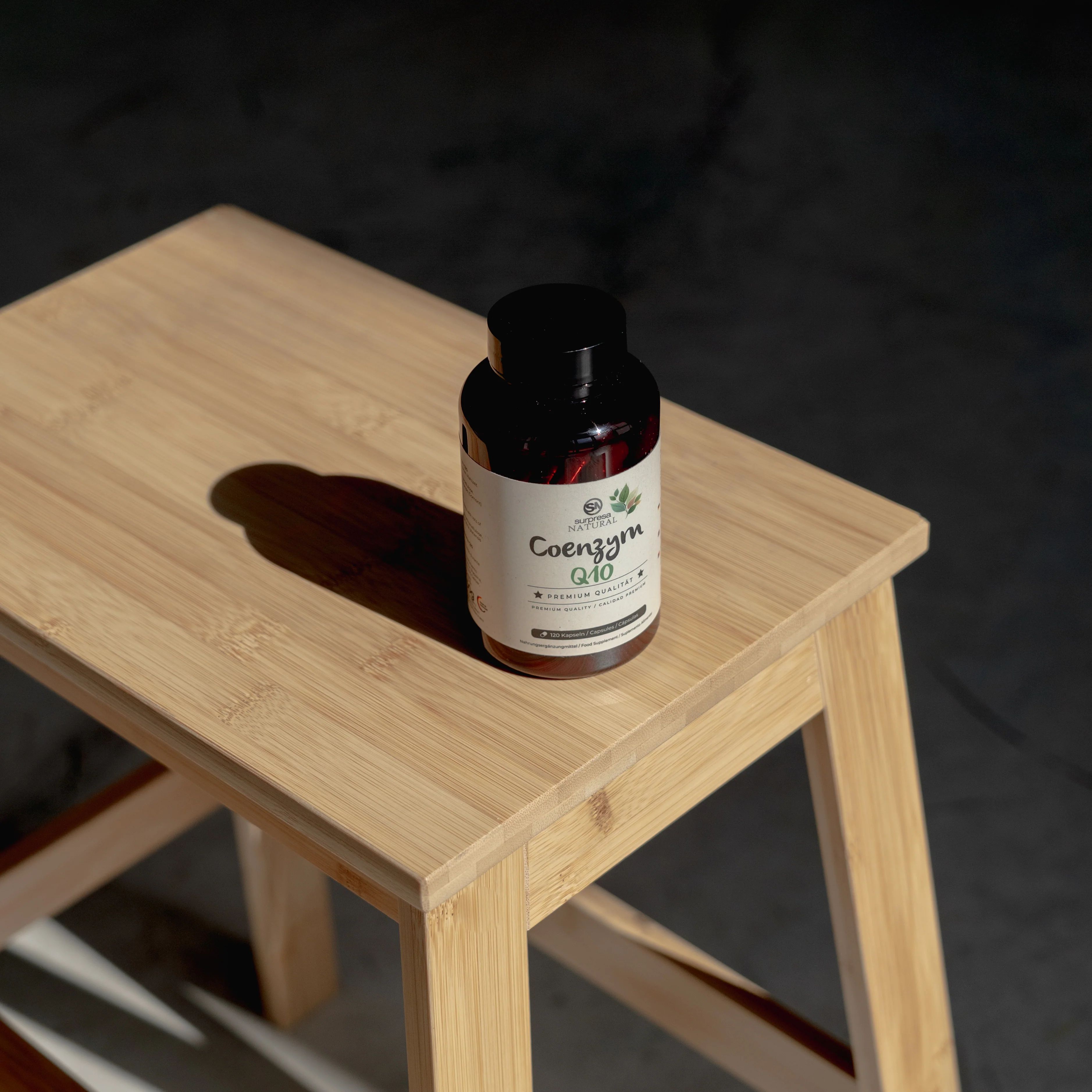 Braune Flasche mit Etikett auf einem kleinen Holzschemel. Aufschrift: Coenzym Q10.