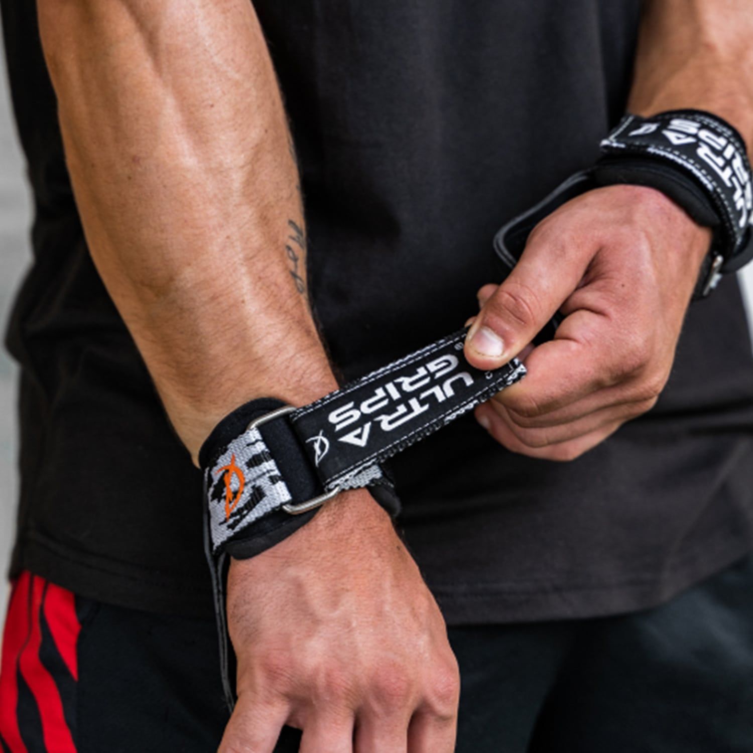 Handgelenkbandagen mit Griff. Schwarzes Band mit weißer Schrift. Metallring. Der Griff ist aus Leder.