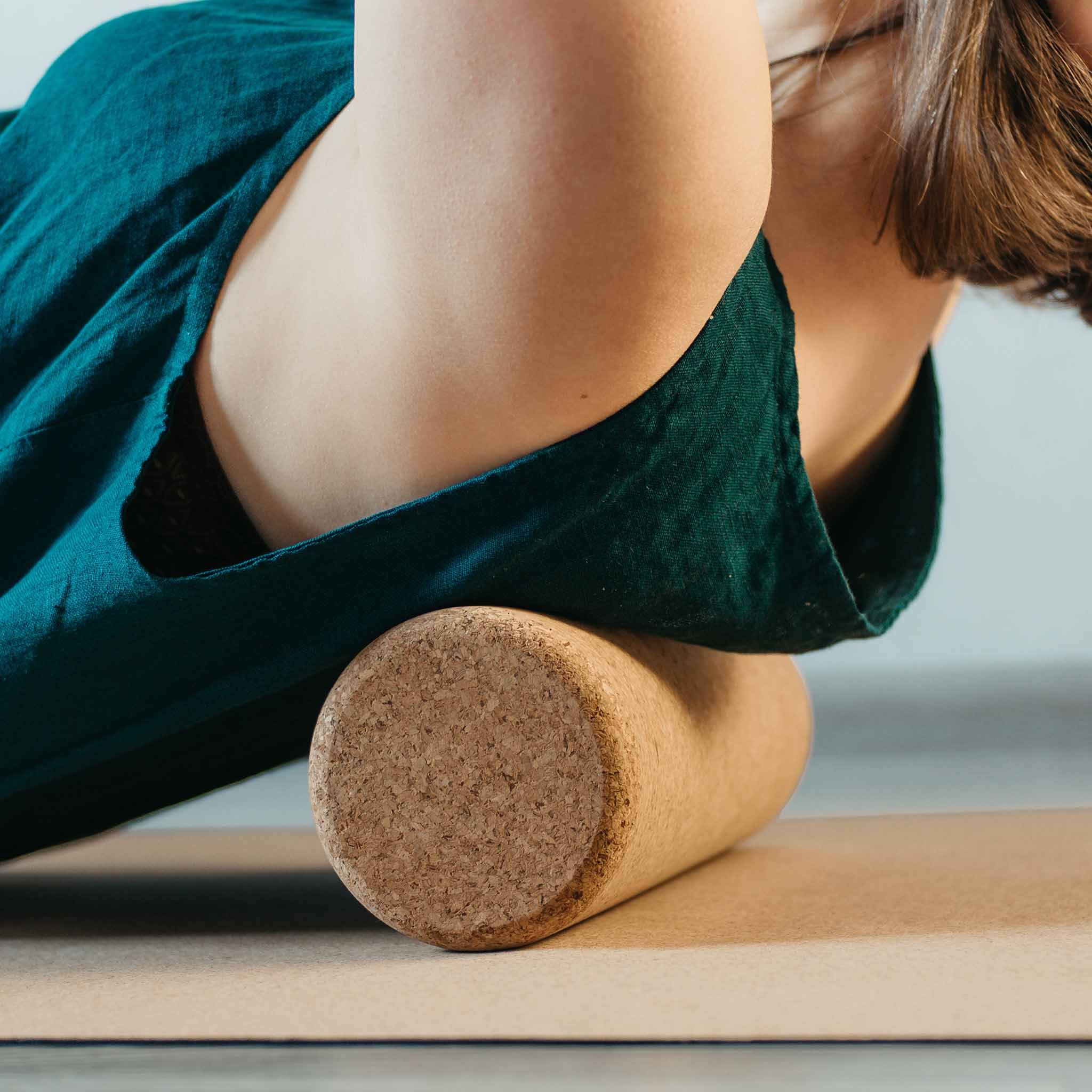 Ein Kork-Massageball wird unter dem oberen Rücken einer Person auf einer Matte gerollt.