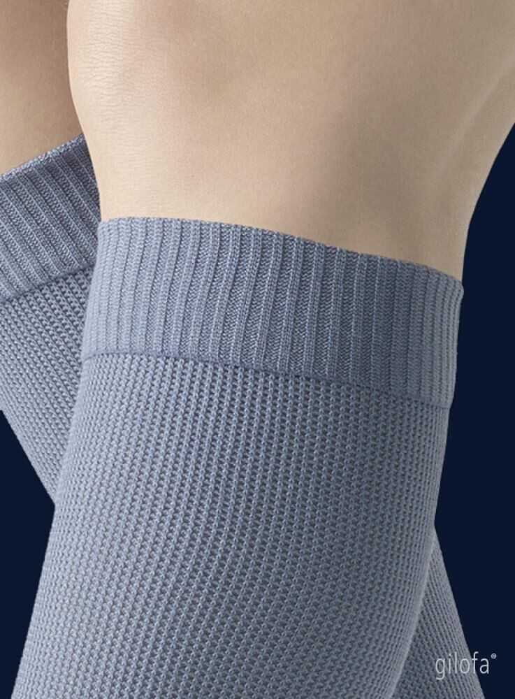 Detailaufnahme des oberen Teils eines hellgrauen Kompressionsstrumpfes. Rippstrickmuster.