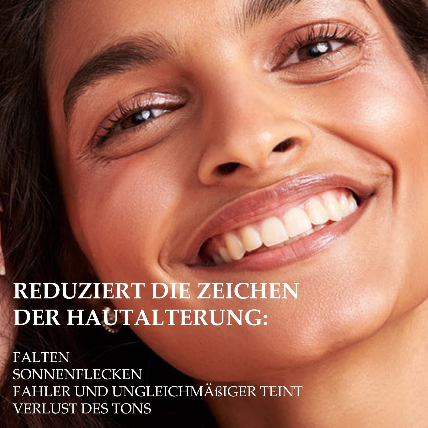 Nahaufnahme eines lächelnden Gesichts. Text: Reduziert die Zeichen der Hautalterung: Falten, Sonnenflecken, fahler Teint, Verlust des Tons.