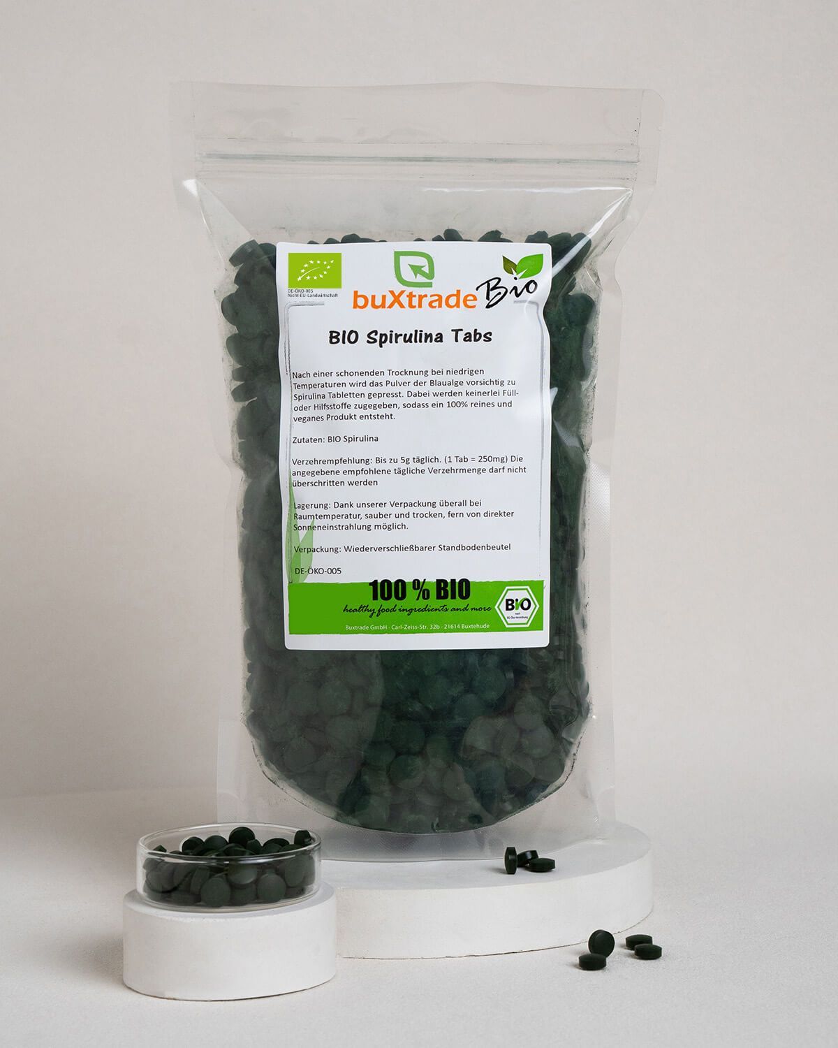 Verpackung mit buxtrade Bio Spirulina Tabs, daneben kleine Schale mit Tabletten.