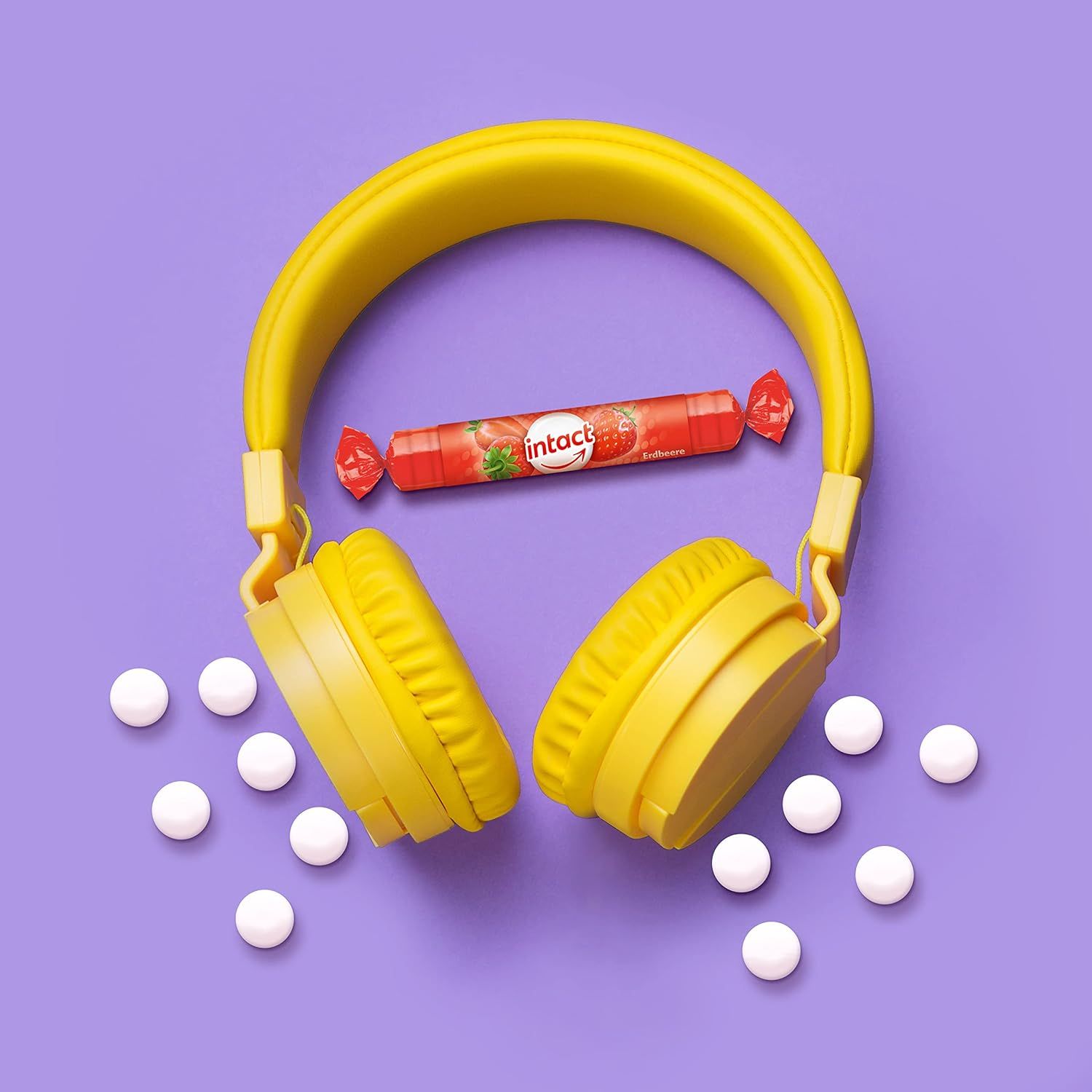 Gelbe Kopfhörer und eine rote Rolle Traubenzucker. Daneben weiße Tabletten. Aufschrift: intact.