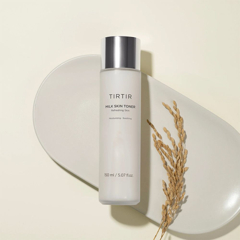 TIRTIR Milk Skin Toner. Weiße Flasche mit silbernem Deckel. Aufschrift: Milk Skin Toner. Auf einem Tablett mit Getreideähre.