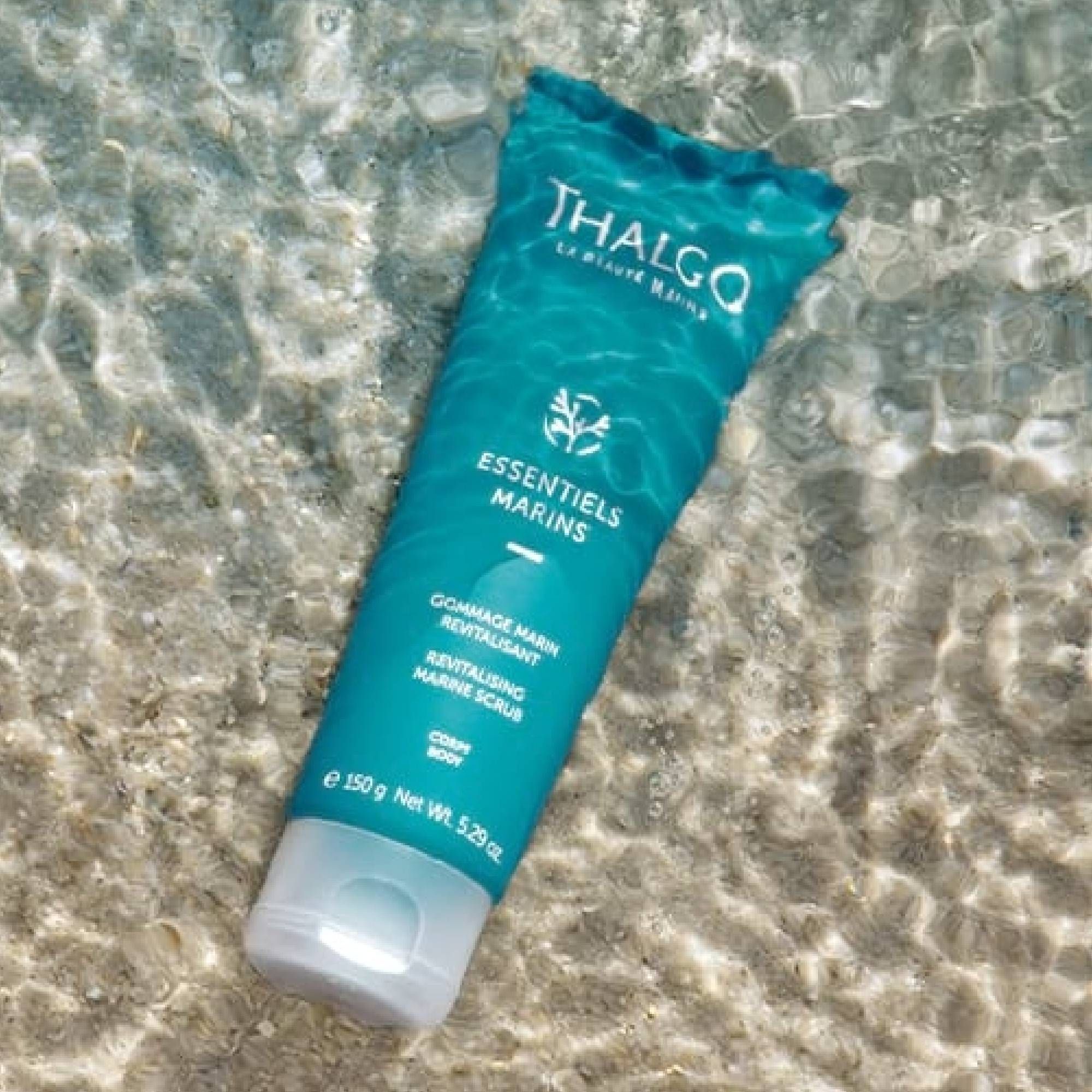 Türkisfarbene Tube im Wasser. Aufschrift: THALGO, ESSENTIELS MARINS, Gommage Marin Revitalisant, Revitalizing Marine Scrub. 150g.