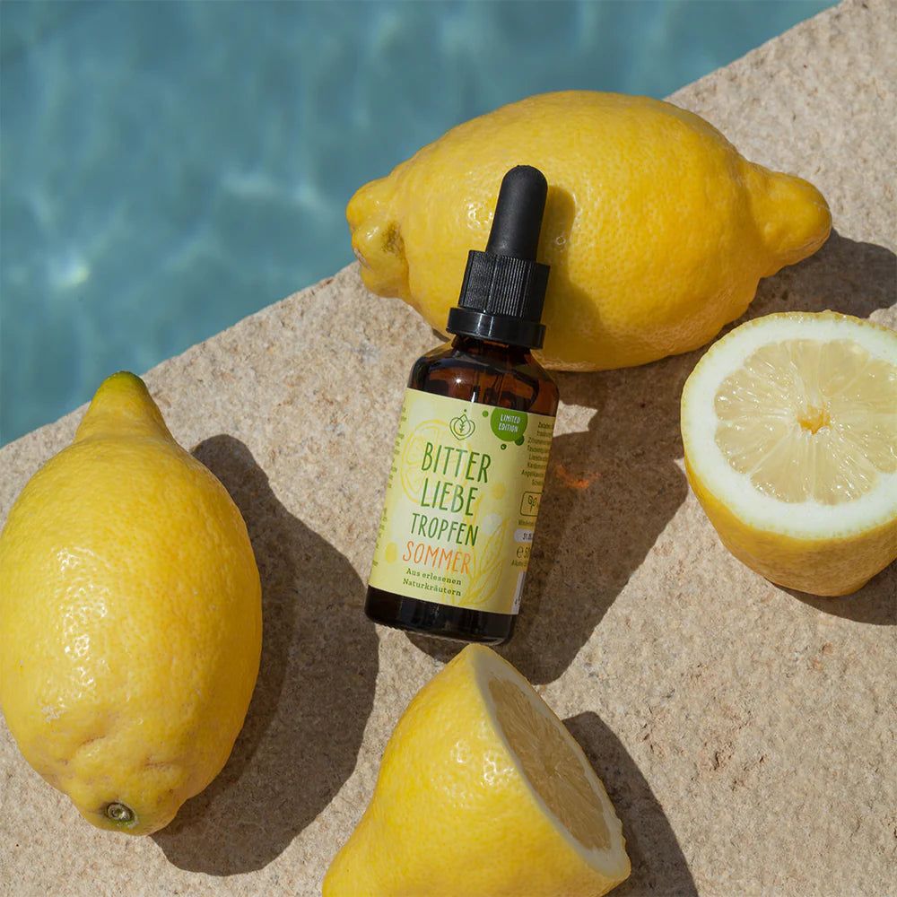 Braune Flasche mit Pipette, umgeben von Zitronen. Auf dem Etikett steht "BitterLiebe Tropfen Sommer".