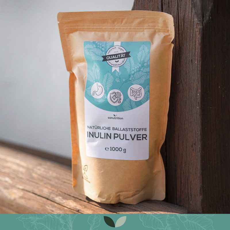 Sanutrition Inulin Pulver in braunem Beutel. Aufdruck: 100% Qualität, Inulin Pulver, e 1000 g. Verpackung steht auf Holz.