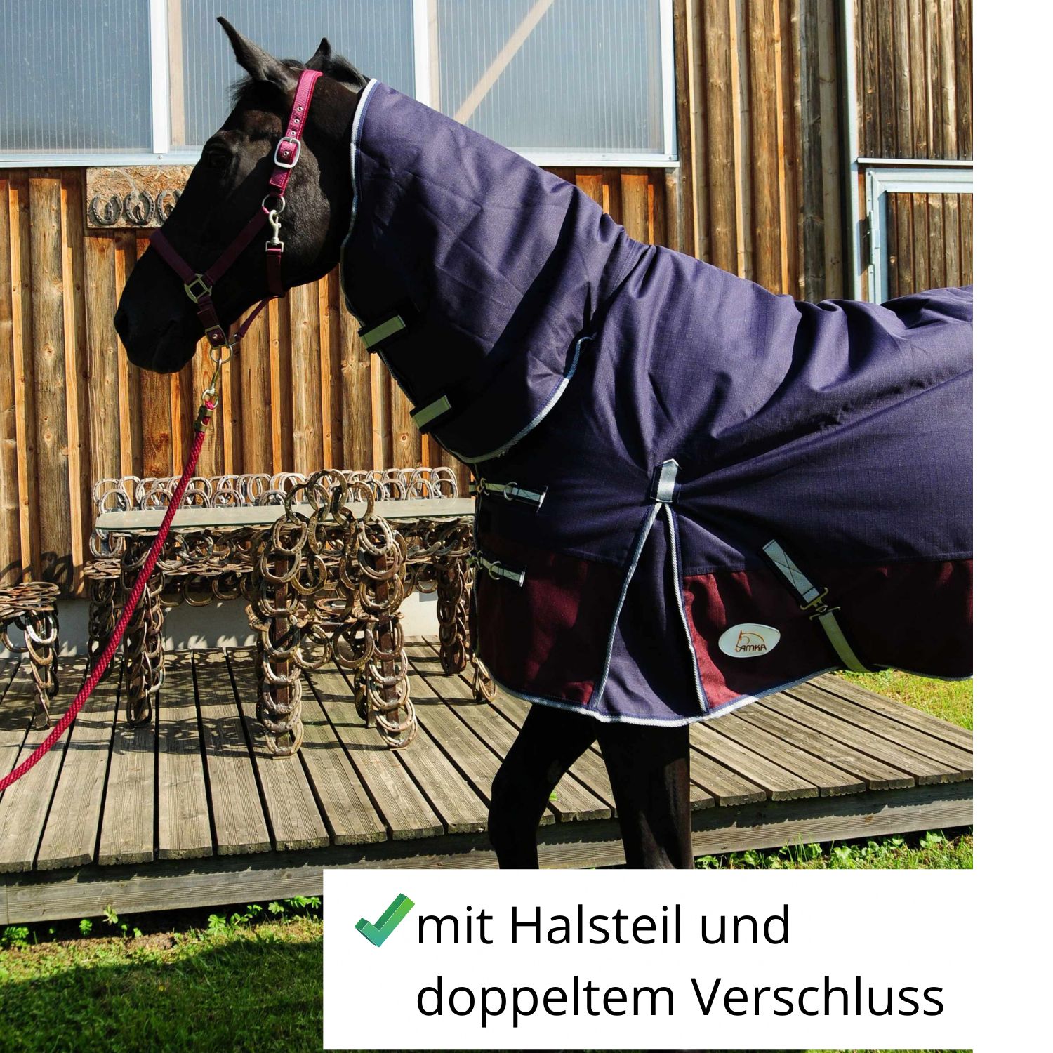 Pferdedecke, dunkelblau mit bordeauxfarbenem Saum. Auf einem Pferd. Text: mit Halsteil und doppeltem Verschluss.