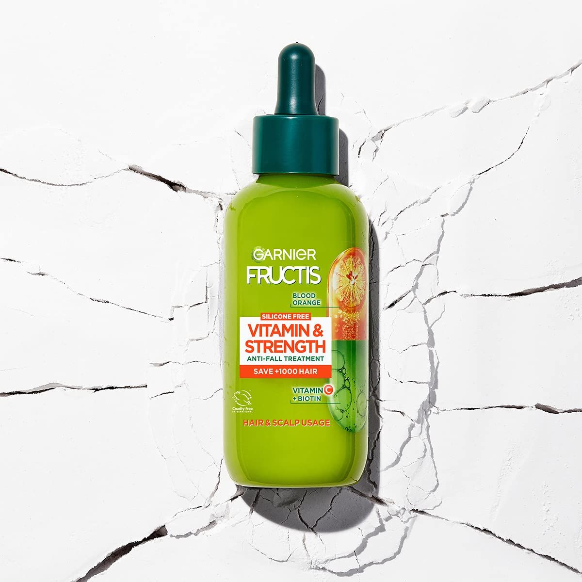 Grüne Flasche mit Tropfer. Aufschrift: Garnier Fructis Vitamine & Kraft. Anti-Haarausfall-Behandlung. Enthält Vitamin C und Biotin.