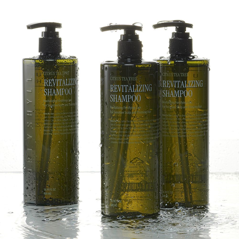 Drei grüne Shampoo-Flaschen mit schwarzen Pumpverschlüssen. Wasser auf den Flaschen. Aufschrift: Revitalizing Shampoo.