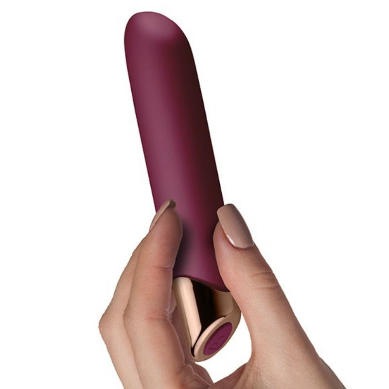 Bordeauxfarbener Vibrator, gehalten von einer Hand. Goldfarbener Akzent am unteren Ende. Runde Form.