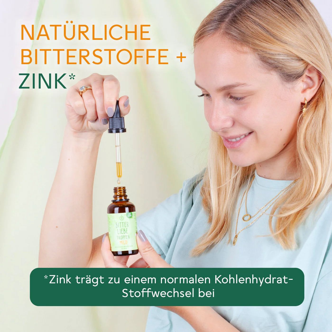 Frau hält Flasche BitterLiebe Tropfen mild mit Pipette. Text: Natürliche Bitterstoffe + Zink. Zink für Stoffwechsel.
