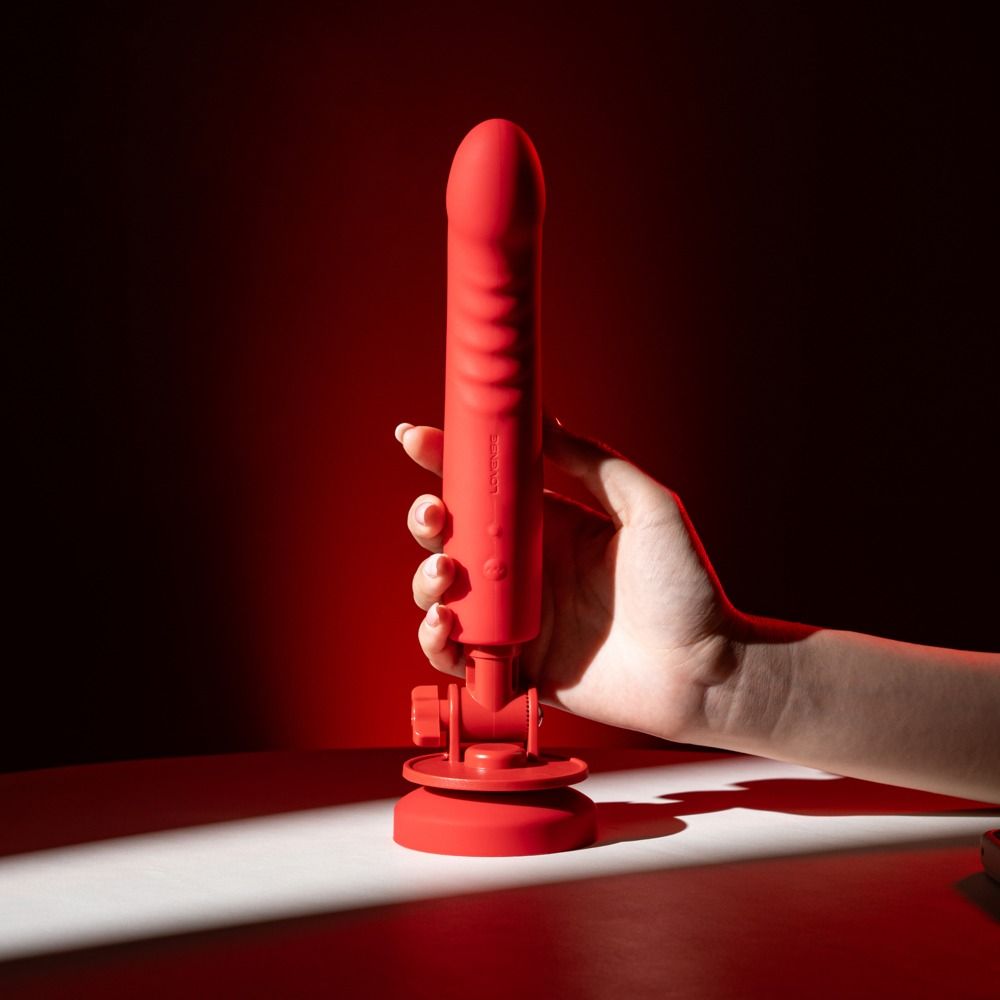 Hand hält einen roten Lovense Mission 2 Vibrator mit Saugnapfhalterung.