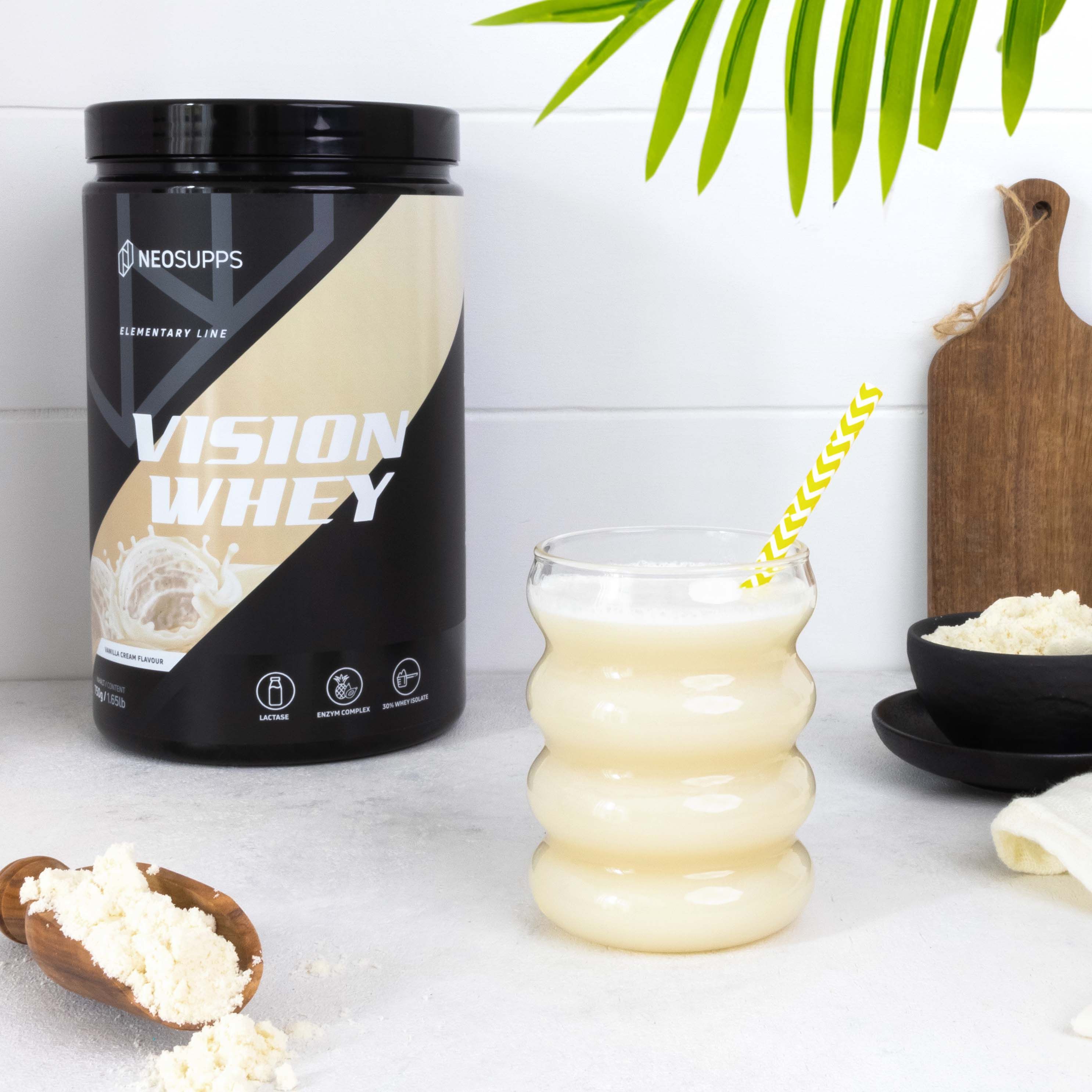 Schwarze Dose "VISION WHEY" neben Glas mit Getränk und Strohhalm. Holzbrett und Löffel mit Pulver.