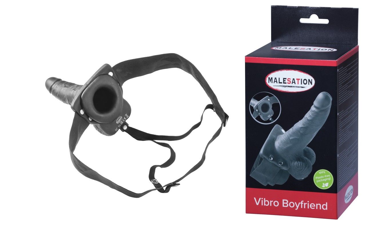 Schwarzes Vibrationsprodukt mit Halterung und Verpackung. Auf der Verpackung steht "MALESATION - Vibro Boyfriend".