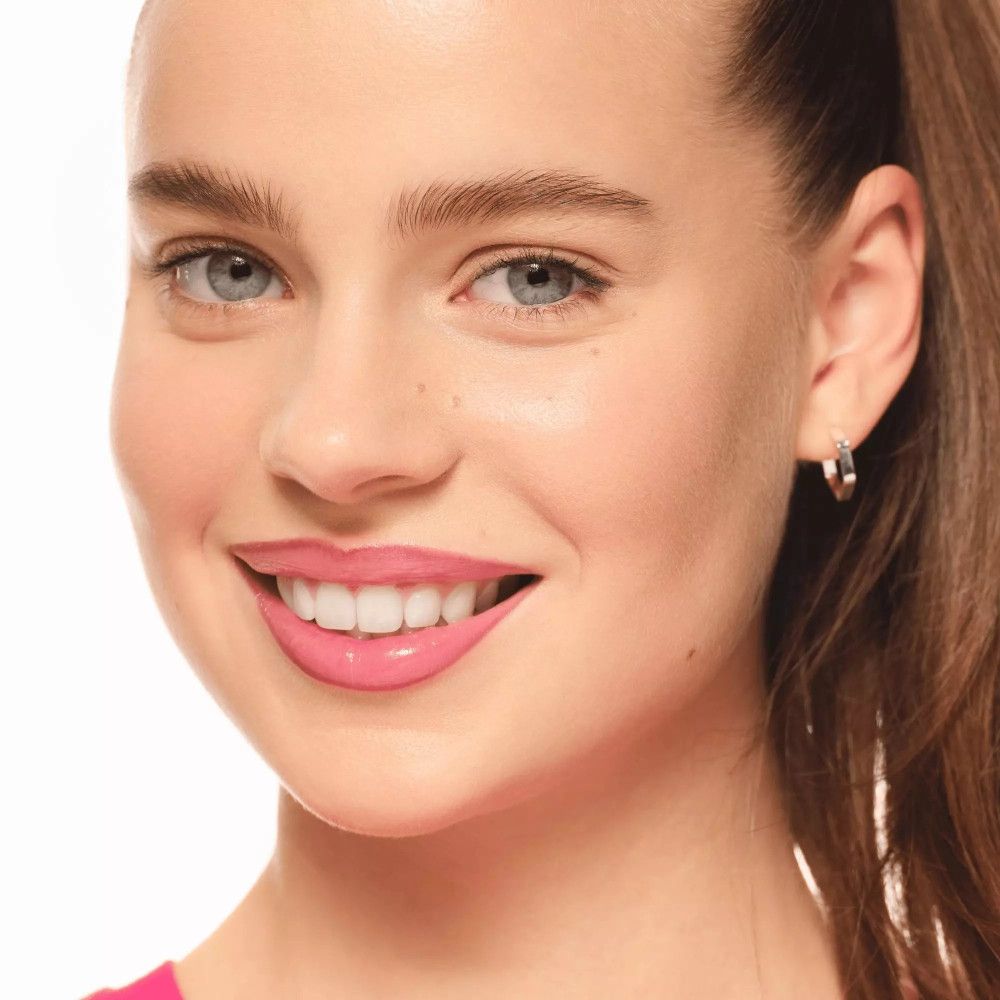 Frau mit rosa Lippenstift. Haut mit Sommersprossen. Silberner Ohrring.
