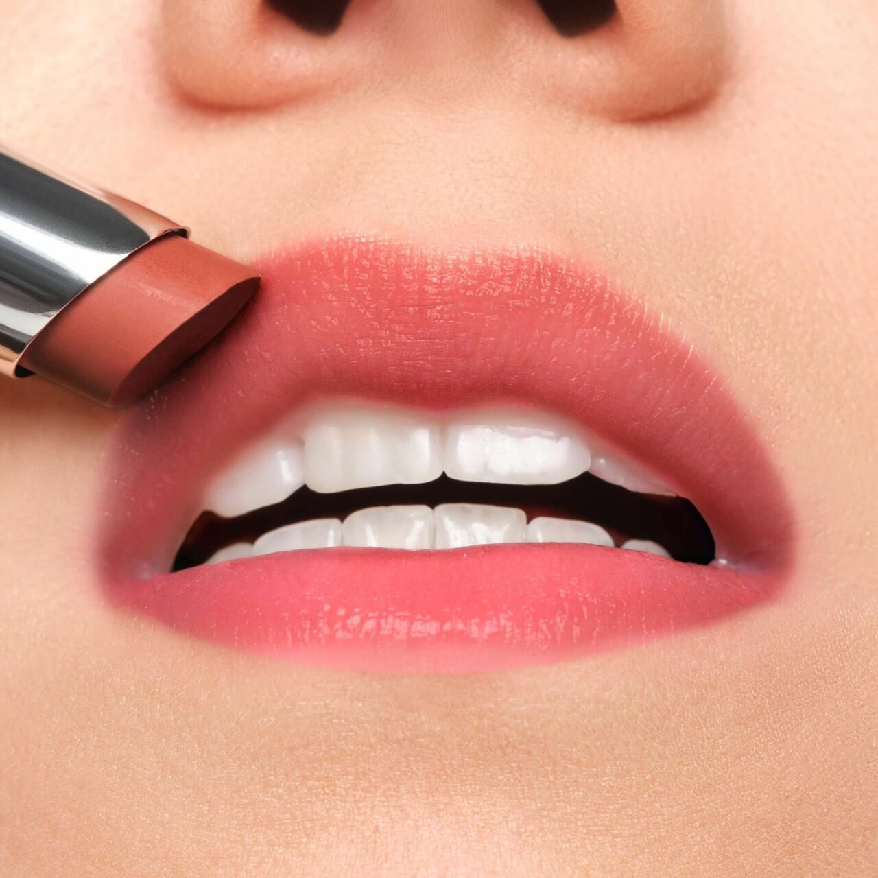 Nahaufnahme von Lippen, die mit einem Lippenbalsam bestrichen werden. Die Lippen sind rosa gefärbt.