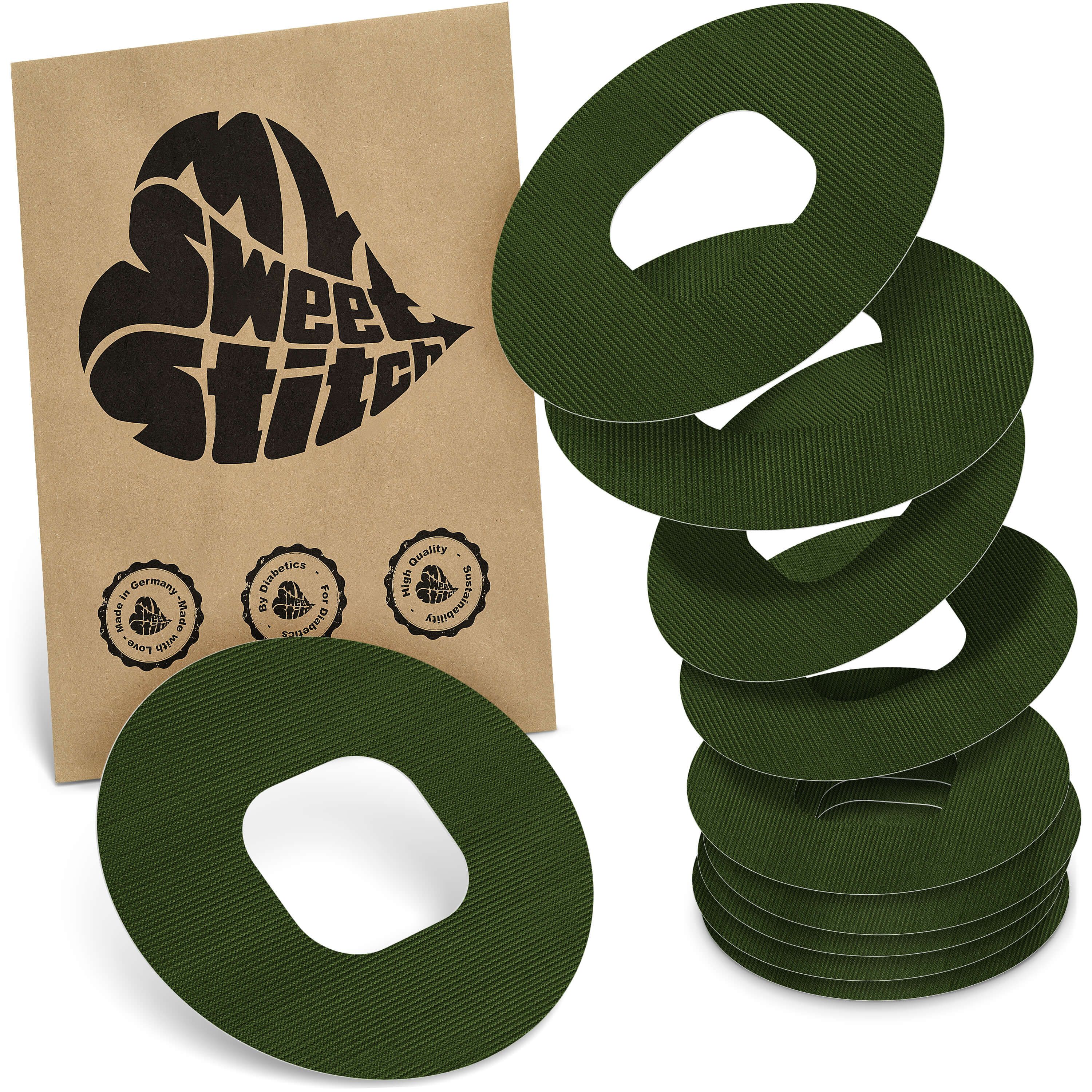 Grüne, ringförmige Pflaster mit Loch in der Mitte. Neben einer braunen Verpackung mit Logo und Siegeln. Mehrere Pflaster gestapelt.