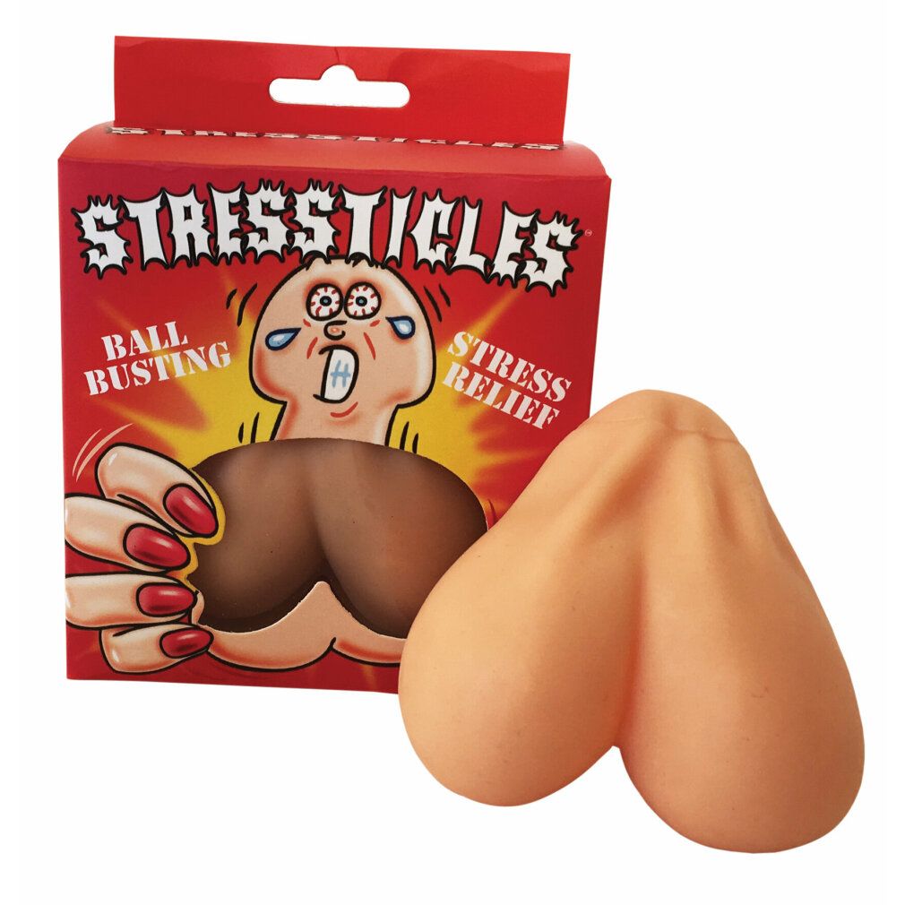 Beige Stressticles neben roter Verpackung. Aufschrift: STRESSTICLES, BALL BUSTING, STRESS RELIEF. Produkt aus Gummi.