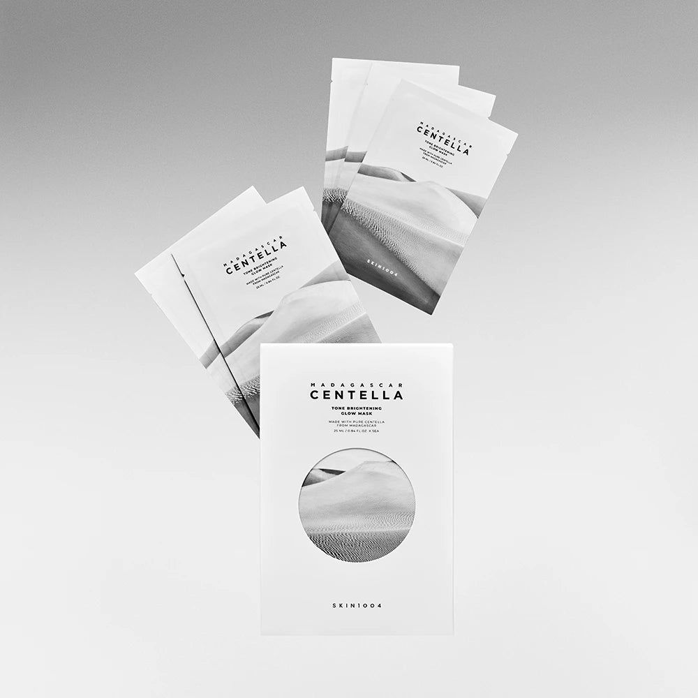 Produktverpackung und Maskenbeutel. Aufschrift: MADAGASCAR CENTELLA. Marke: SKIN1004. Mehrere Beutel schweben über der Verpackung.