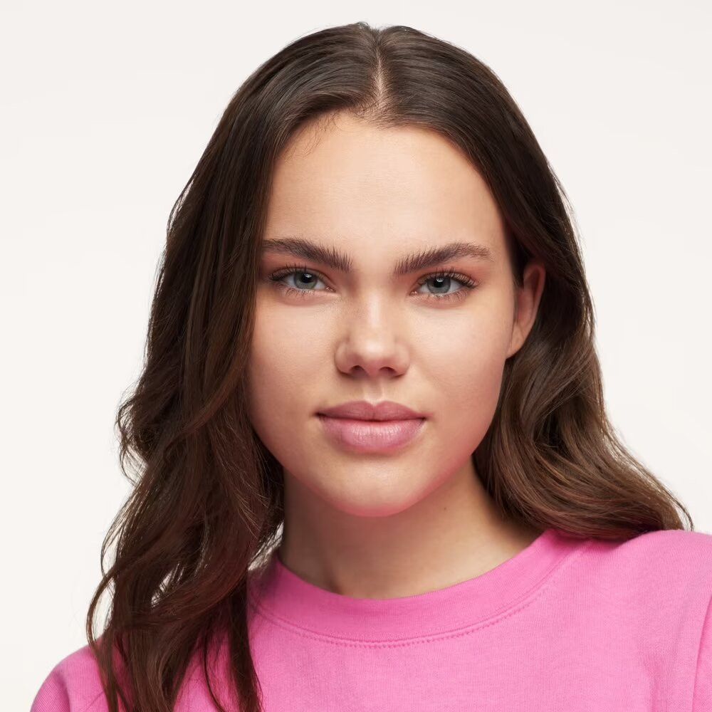 Porträt einer jungen Frau mit rosa Oberteil. Sie blickt direkt in die Kamera.