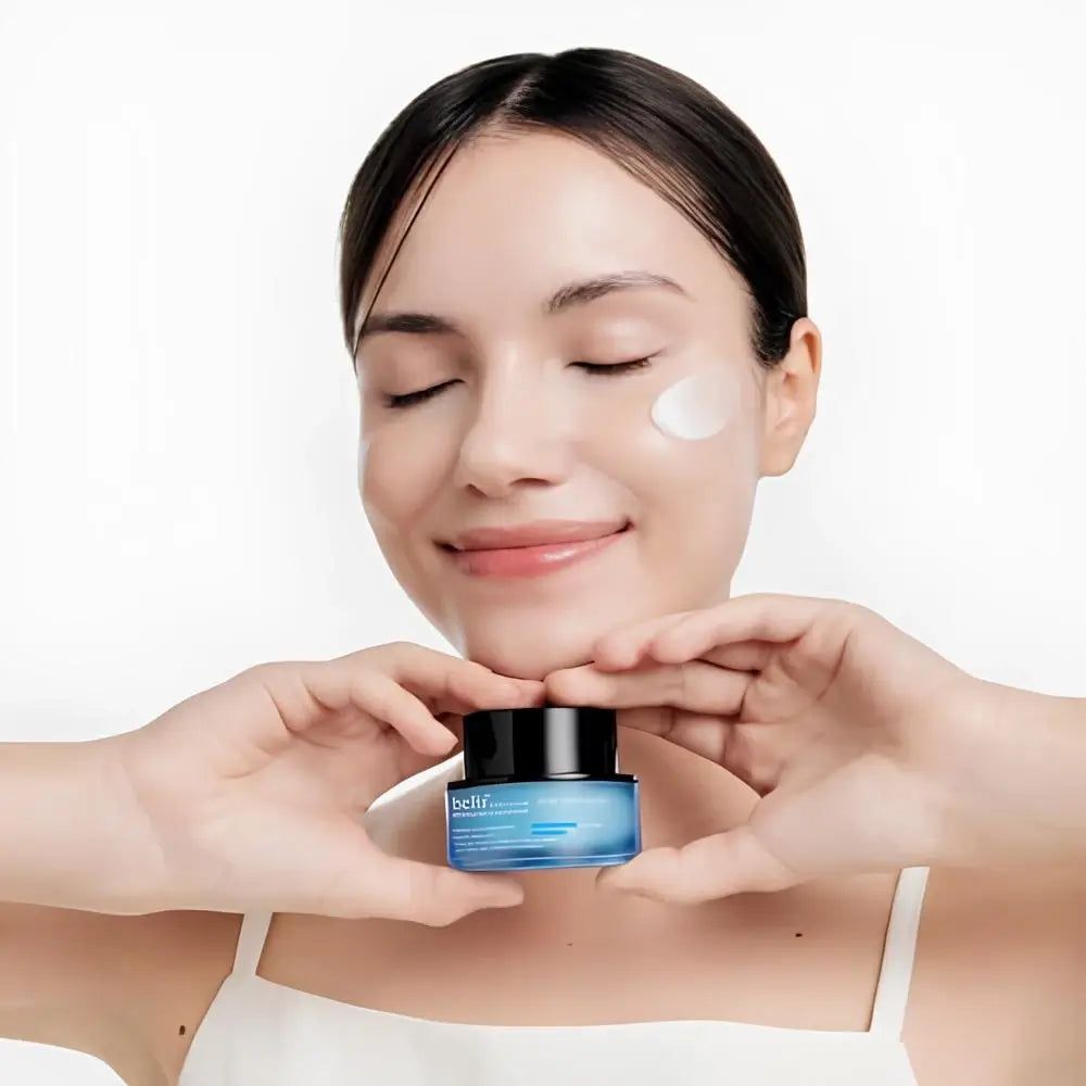 Frau hält ein blaues Tiegel mit schwarzem Deckel. Sie hat Creme auf der Haut.