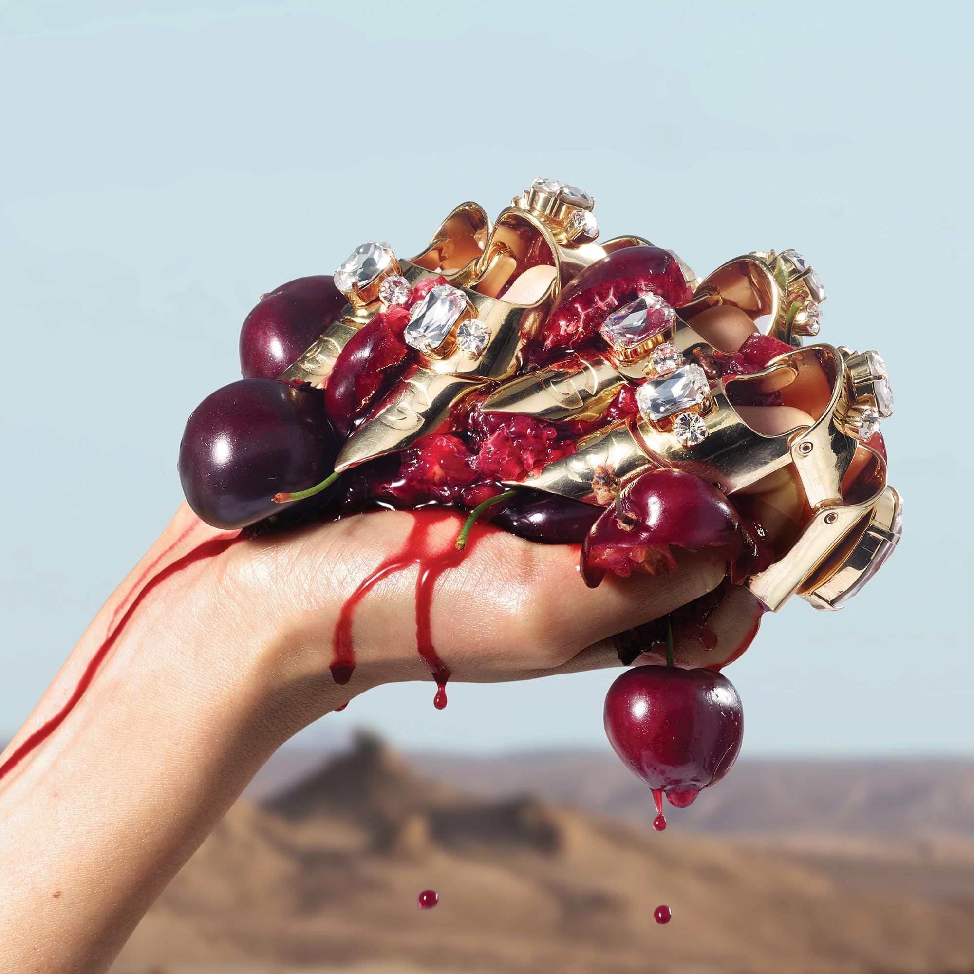 Hand hält Kirschen und goldene Ringe mit Diamanten. Roter Saft tropft. Hintergrund: Landschaft.