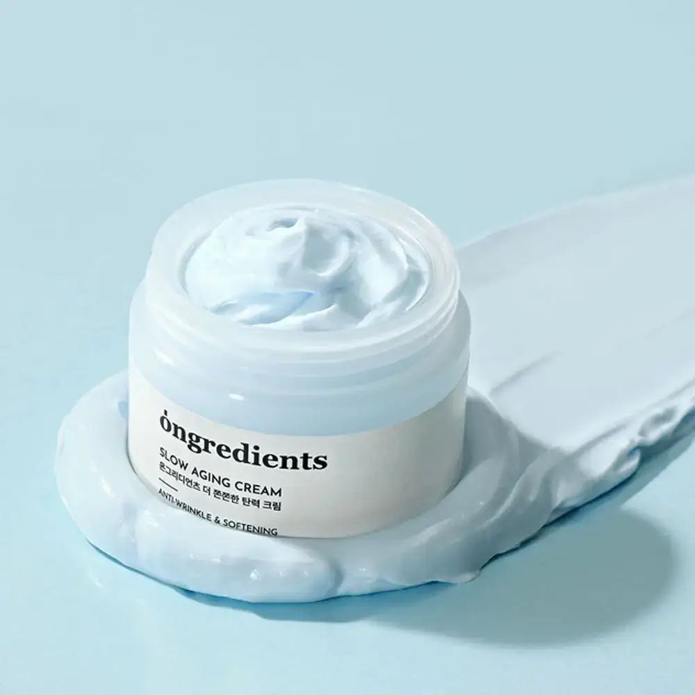 Offenes Creme-Glas mit Creme-Klecks. Aufschrift: Ongredients, Slow Aging Cream, Anti-Wrinkle & Softening.