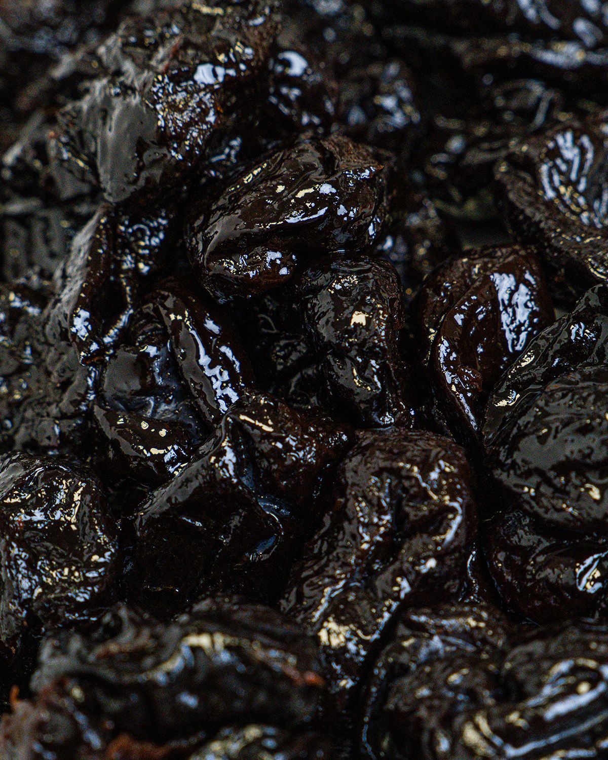 Nahaufnahme von getrockneten Pflaumen. Glänzende, dunkle Oberfläche, leicht runzelig.